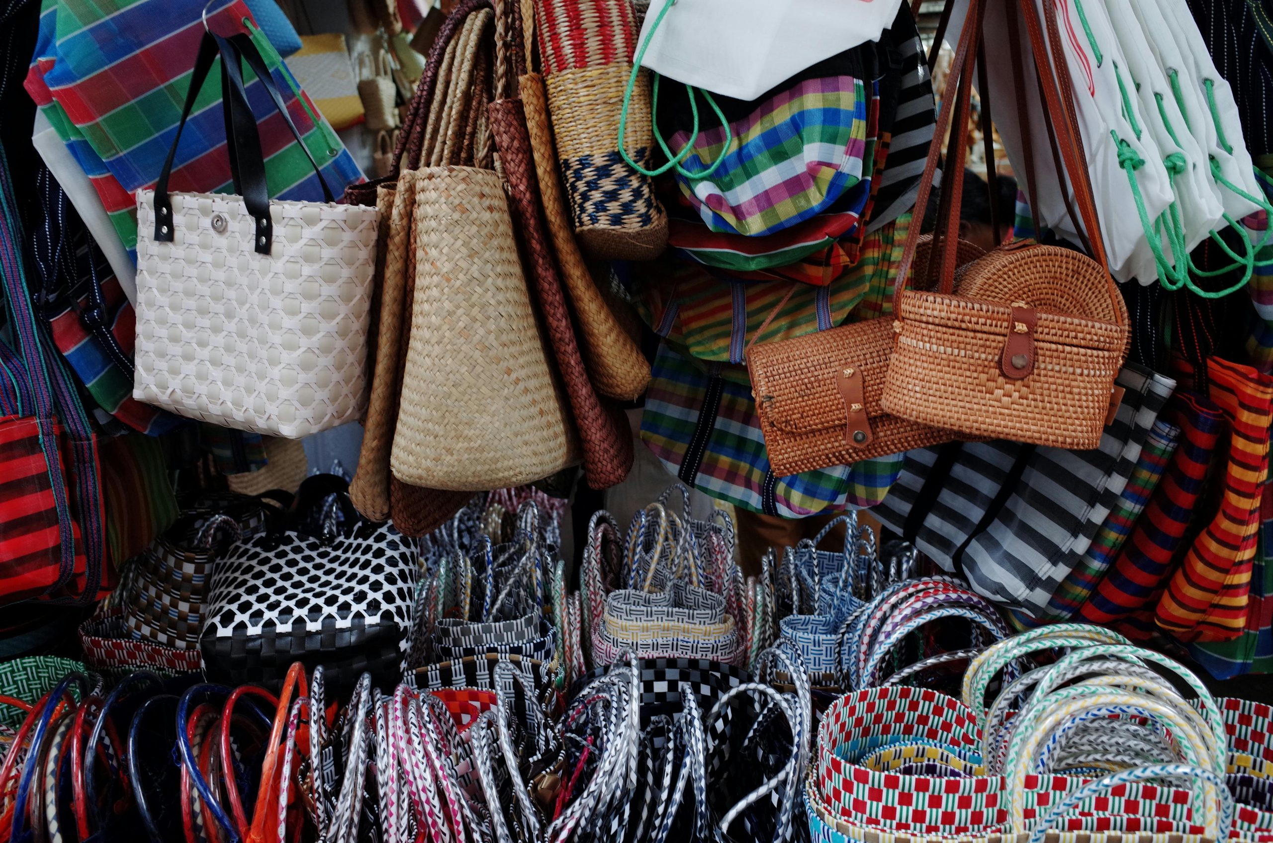 Vibrant display of handmade woven bags at a street market, perfect for fashion enthusiasts.
